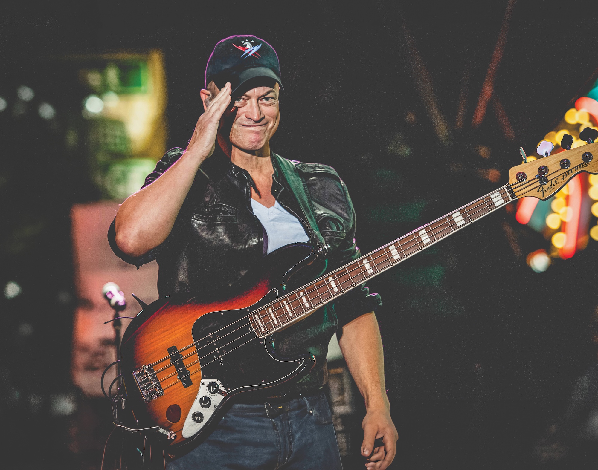 Gary Sinise with a guitar saluting the camera