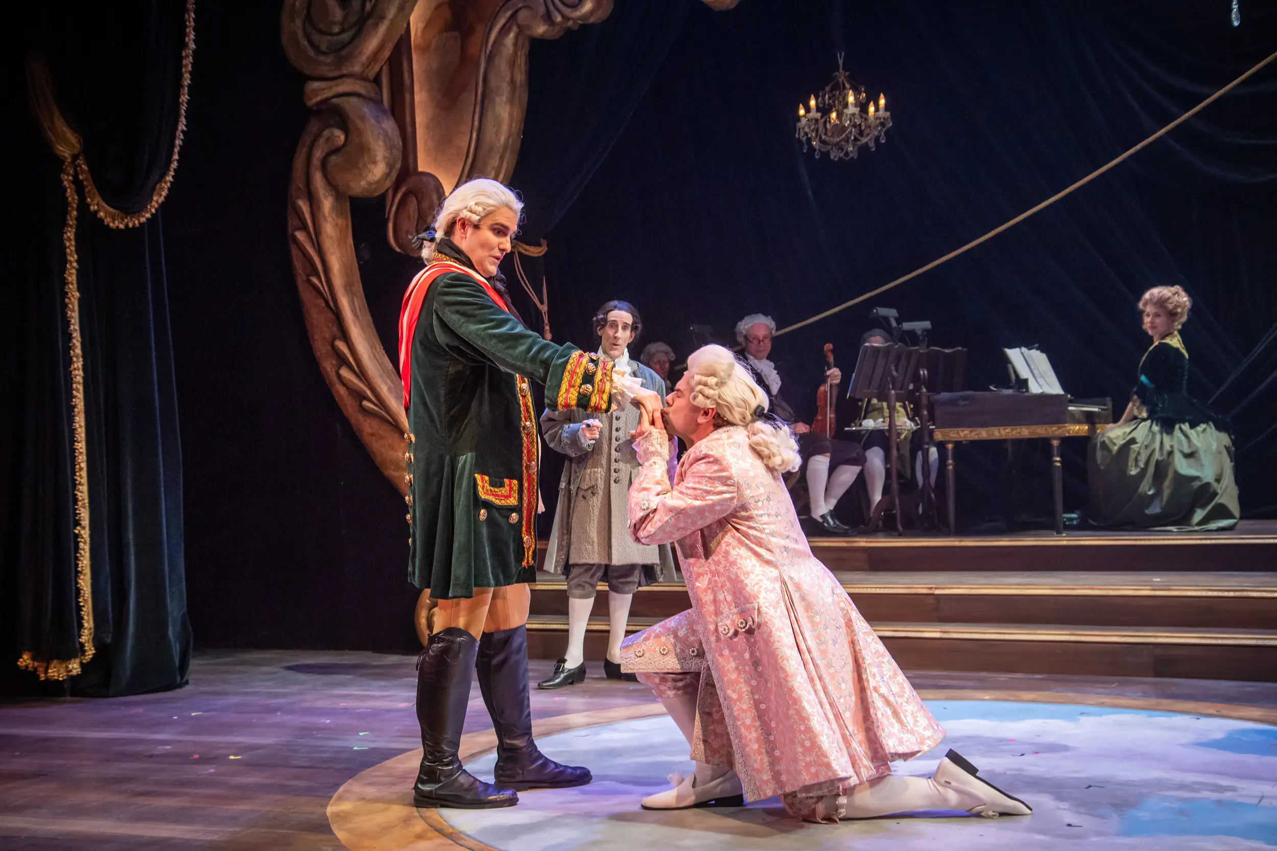 Amadeus performance with a man kneeling and kissing another man's hand.
