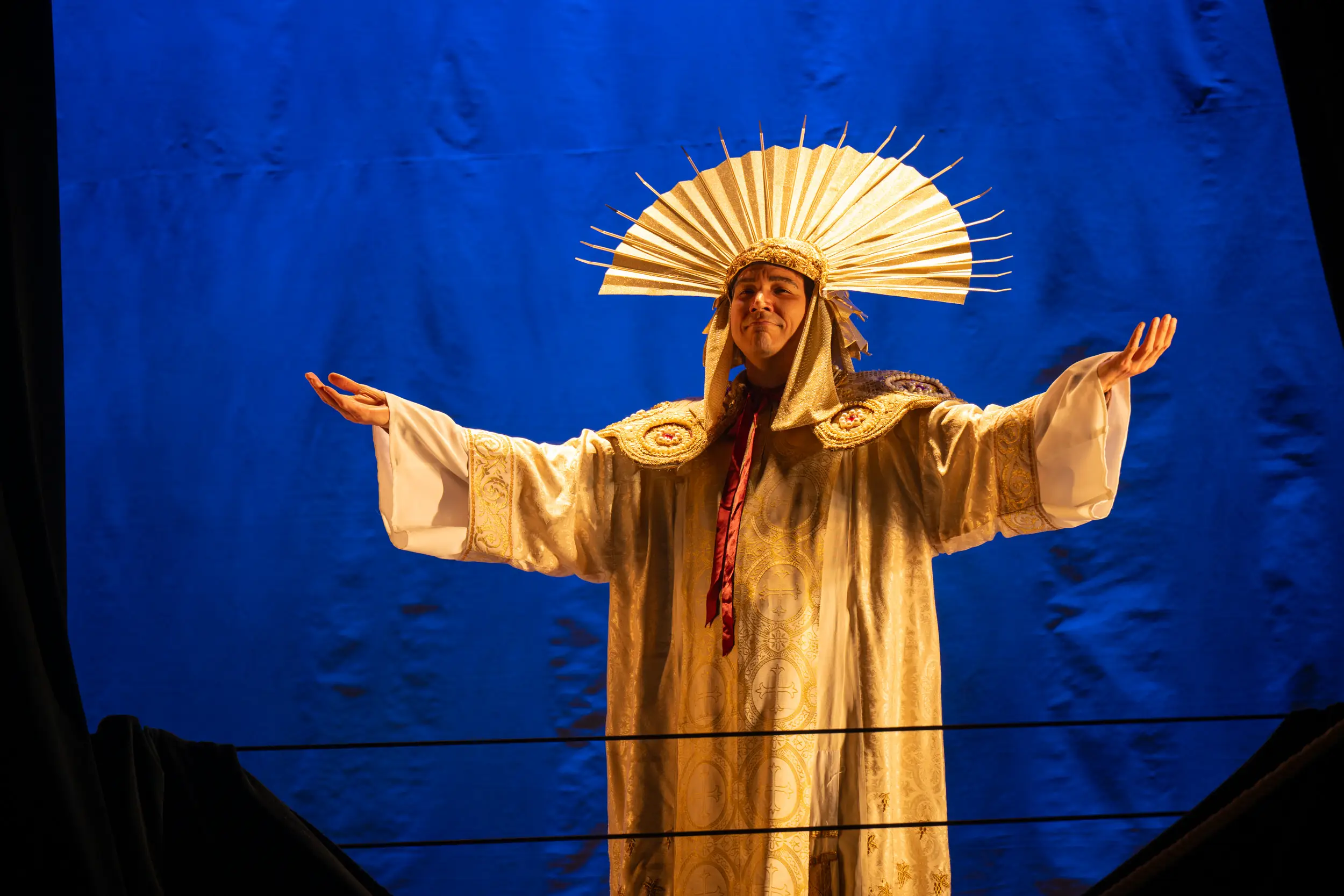 Man with fan hat and robe on stage for a performance of Amadeus.
