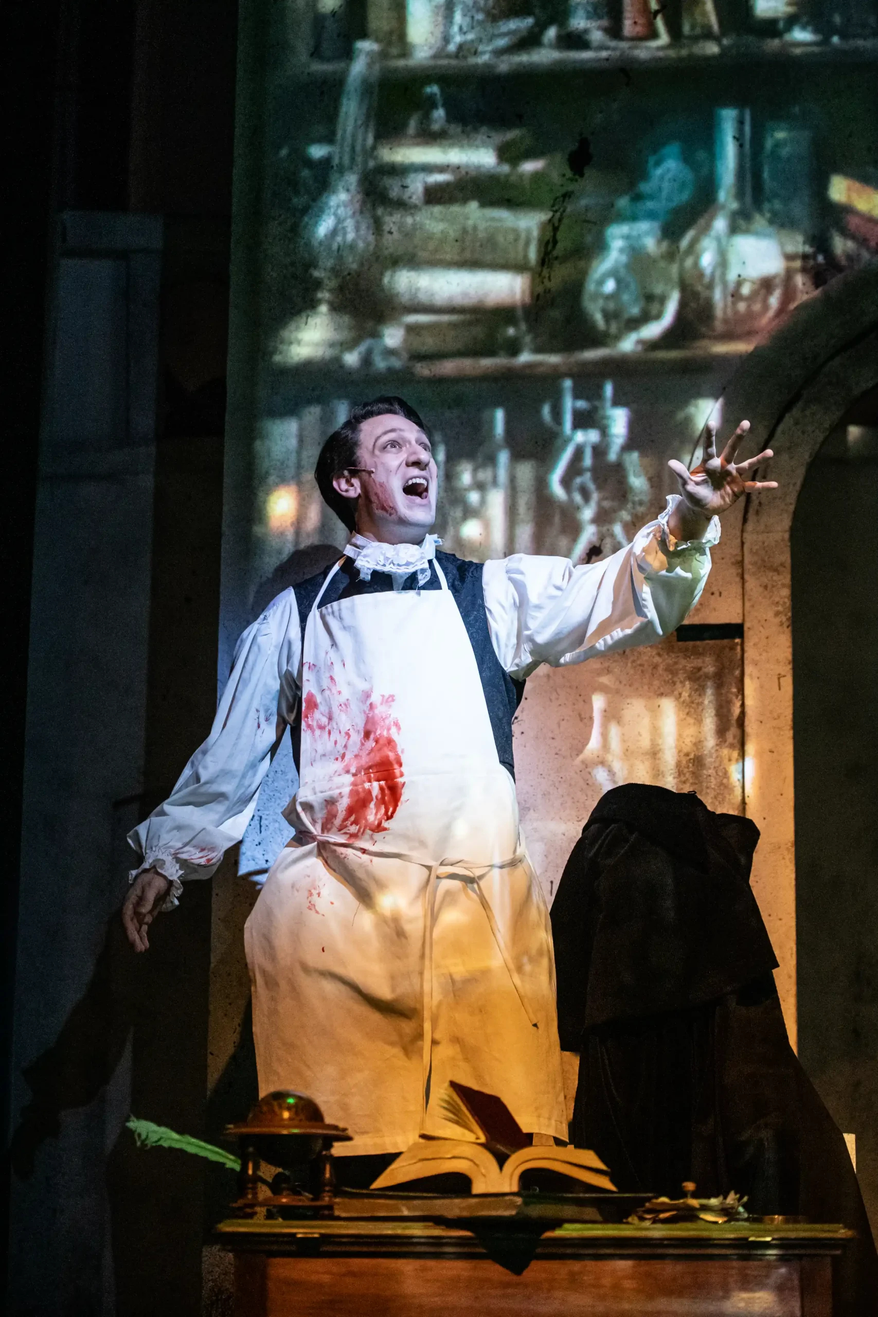 One man with a bloody apron on stage singing during Frankenstein performance