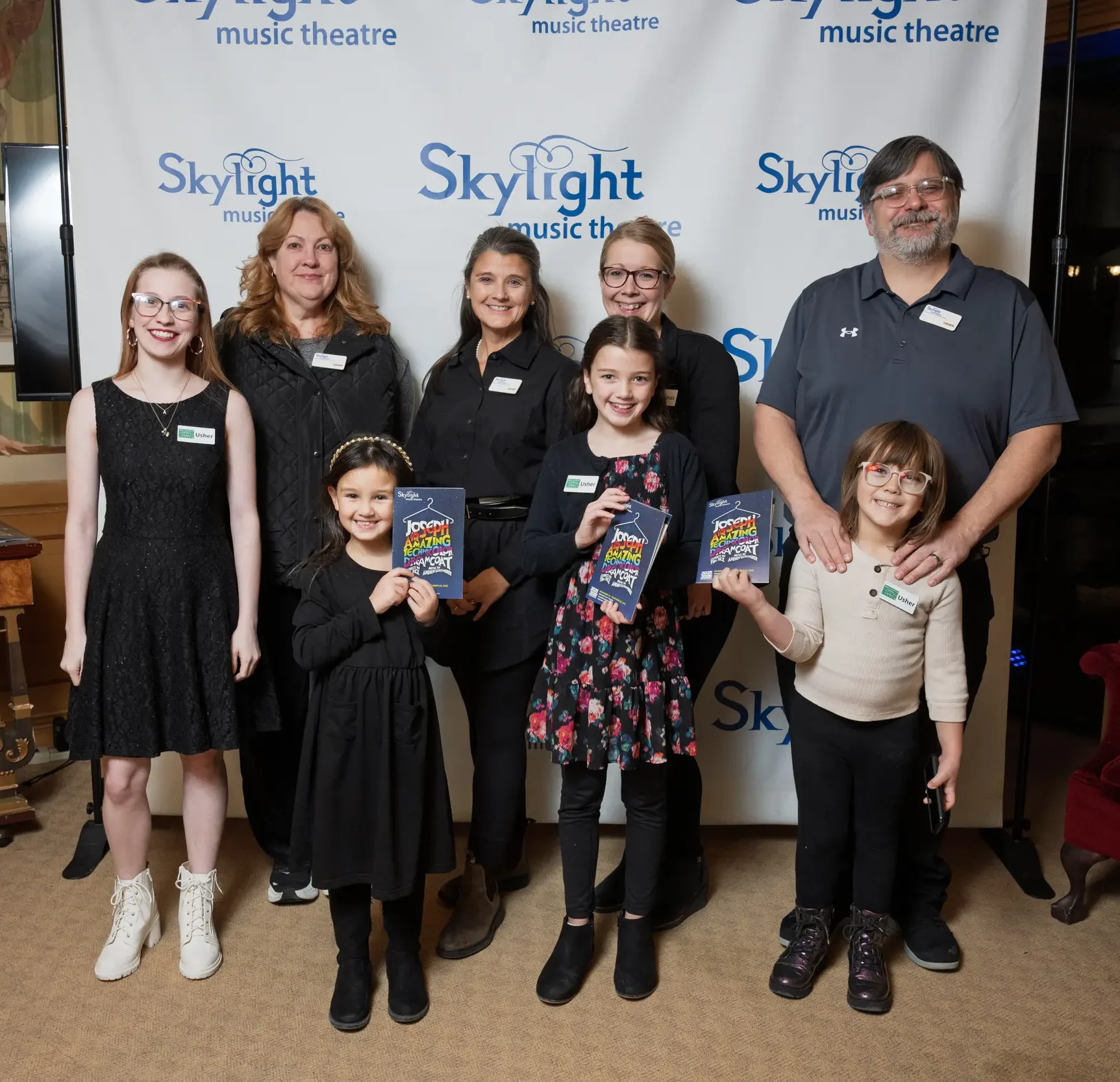 Family in front of the skylight backdrop holding up the playbill