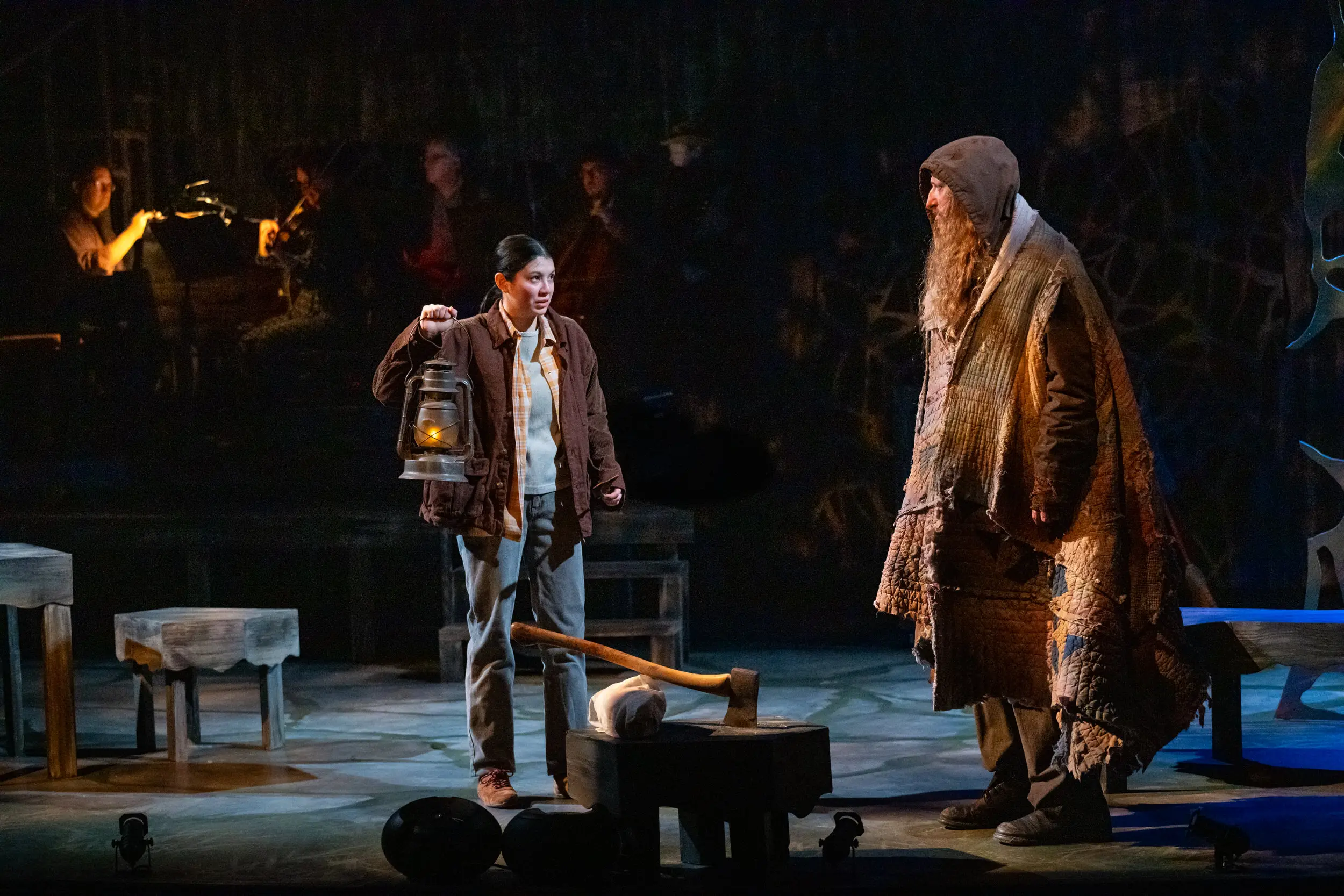 Woman with lantern and large man in hooded robe on stage as part of Spitfire Grill performance