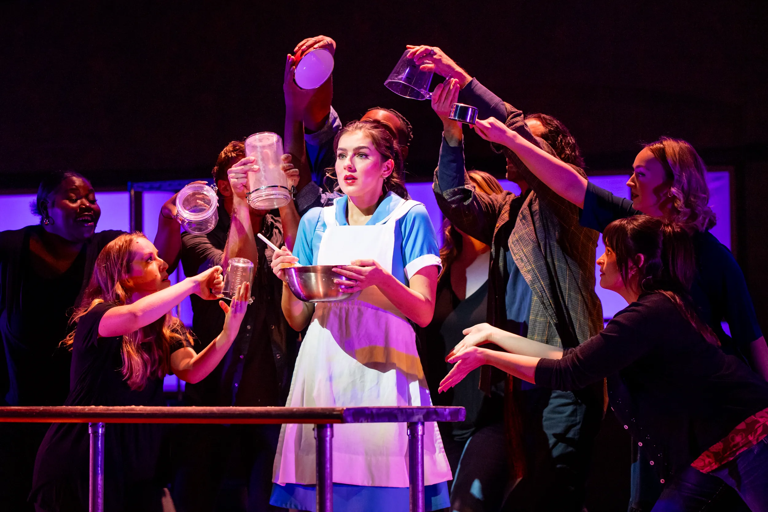 Woman singing and surrounded by cast during Waitress performance