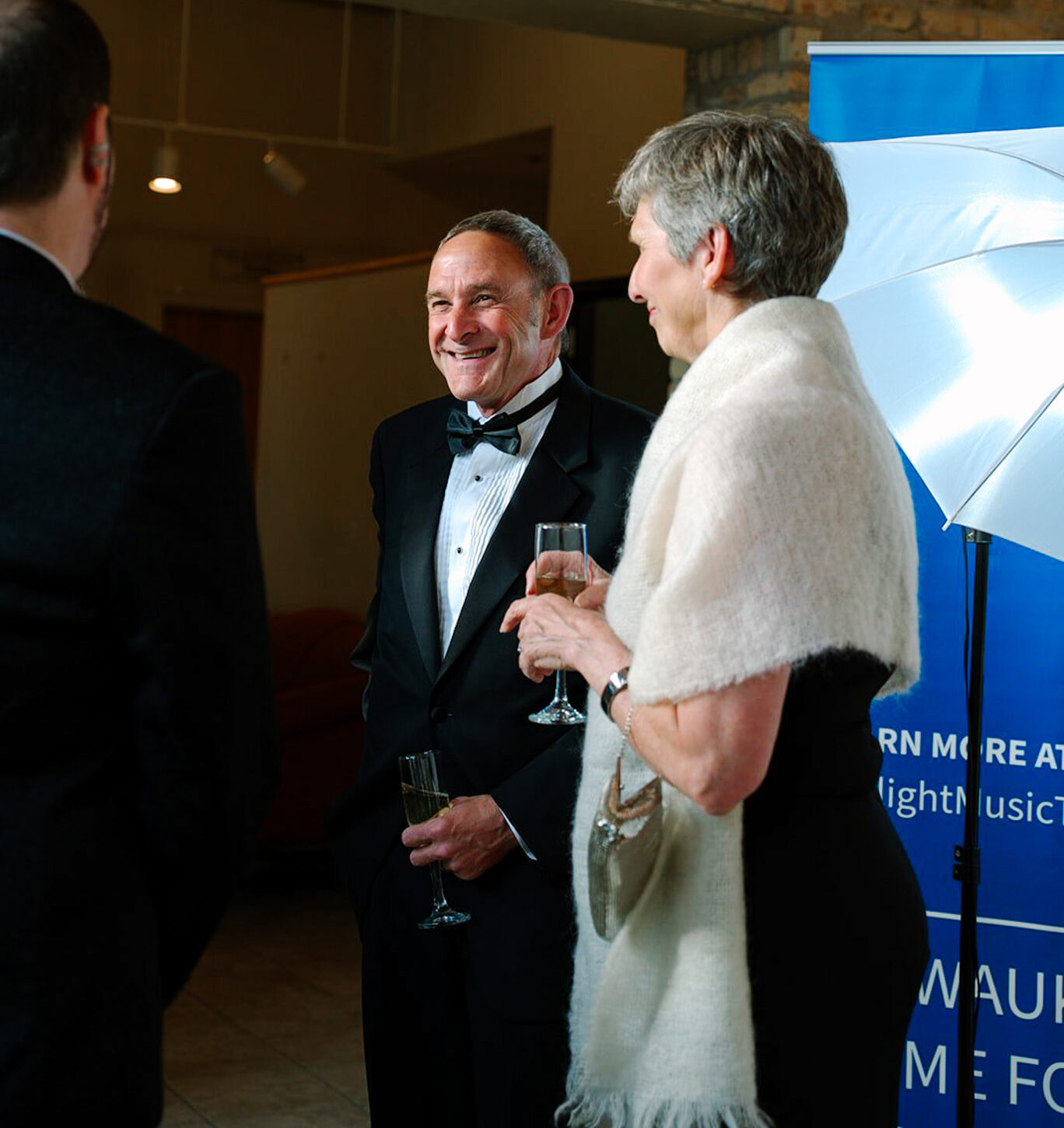 A man and woman in black tie apparel holding glasses of champagne